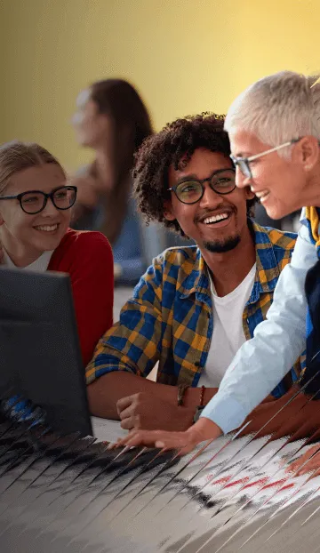 A trainer meets with some new employees at their work station, smiling while they go over a topic