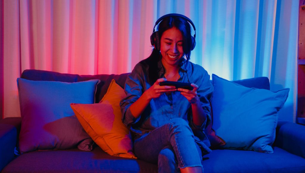 Woman sitting on the couch playing a mobile game