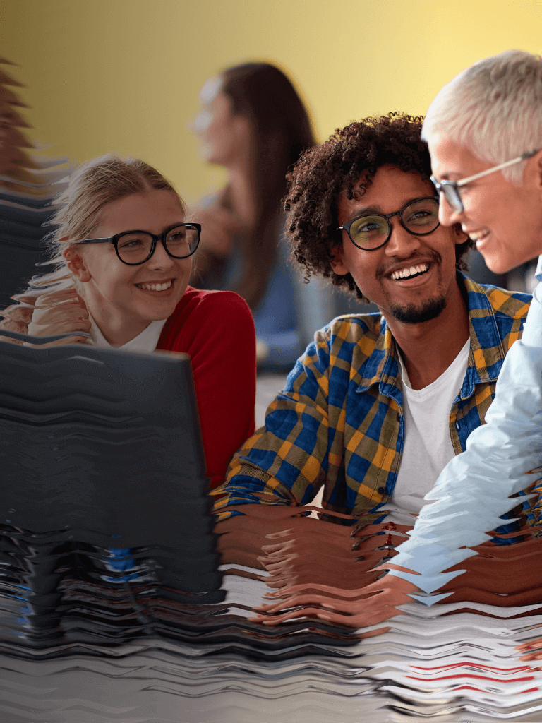 A trainer meets with some new employees at their work station, smiling while they go over a topic