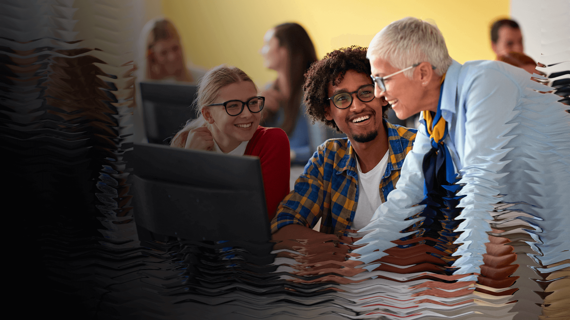 A trainer meets with some new employees at their work station, smiling while they go over a topic