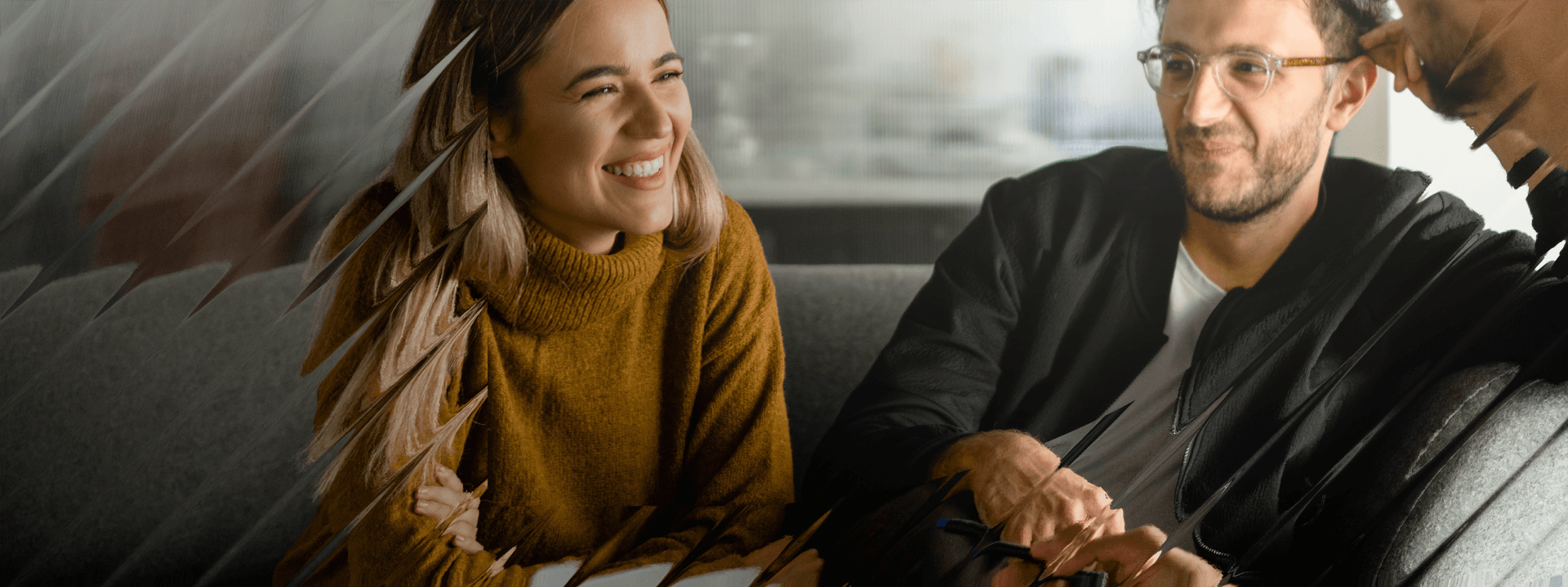 Two people sit in a casual meeting space, smiling while discussing something