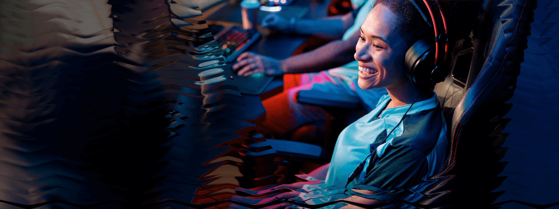 A smiling woman sits at a gaming PC at an event