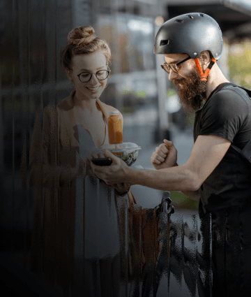 A delivery driver handing lunch to his customer while she pays