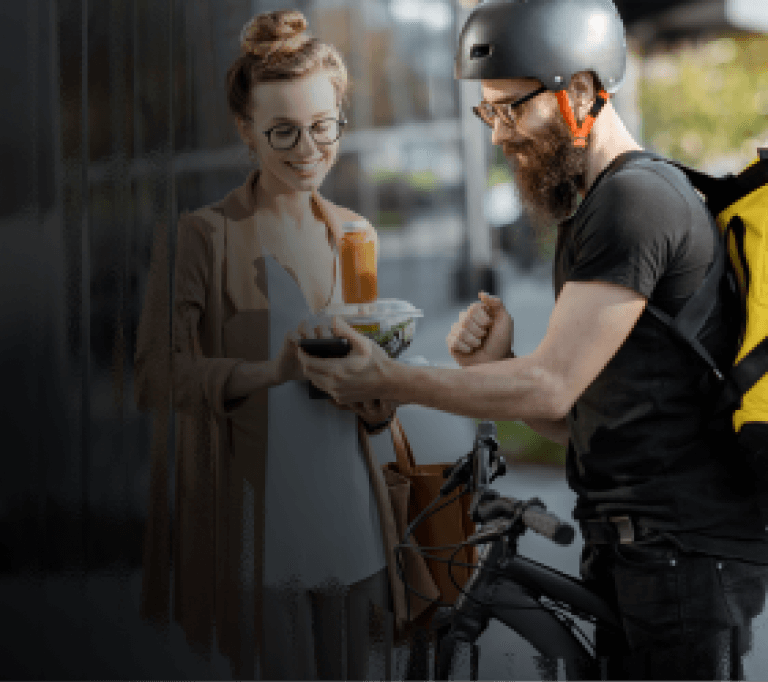 A delivery driver handing lunch to his customer while she pays