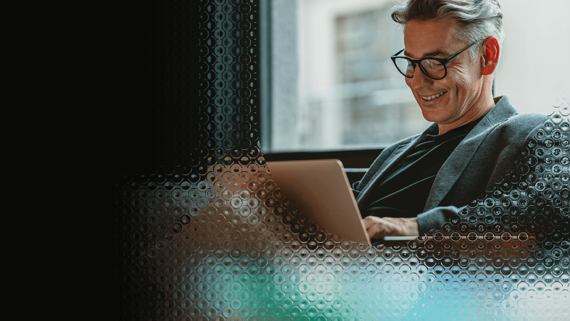  Man in glasses and a blazer, sitting at his laptop, reading an interesting article