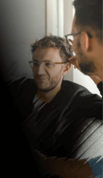 Three people sit in a casual meeting space, smiling while discussing something