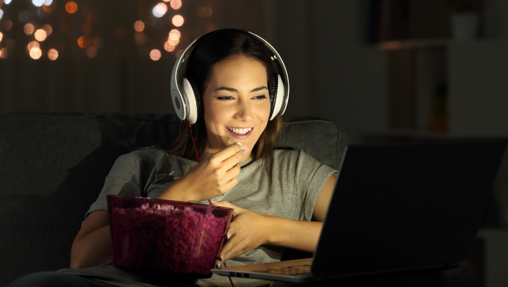 Woman watching a movie on her laptop while holding a bowl of popcorn