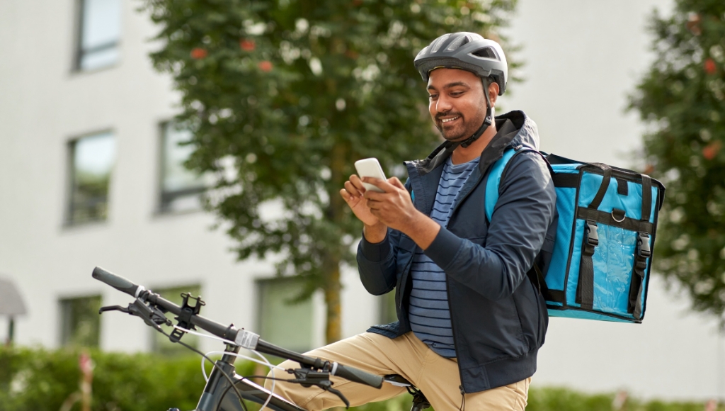 Smiling delivery man looking at his phone