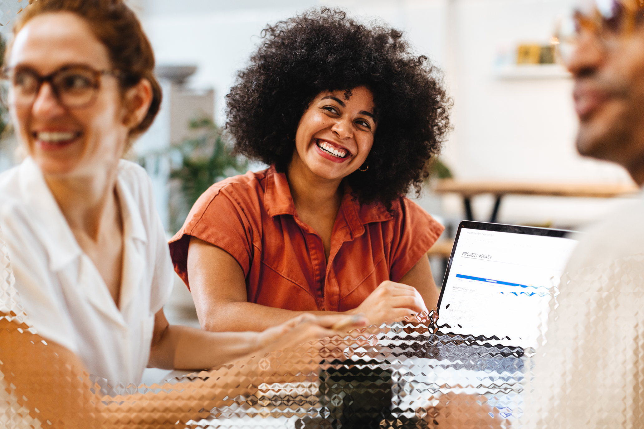 Happy woman presenting her laptop to her colleagues.