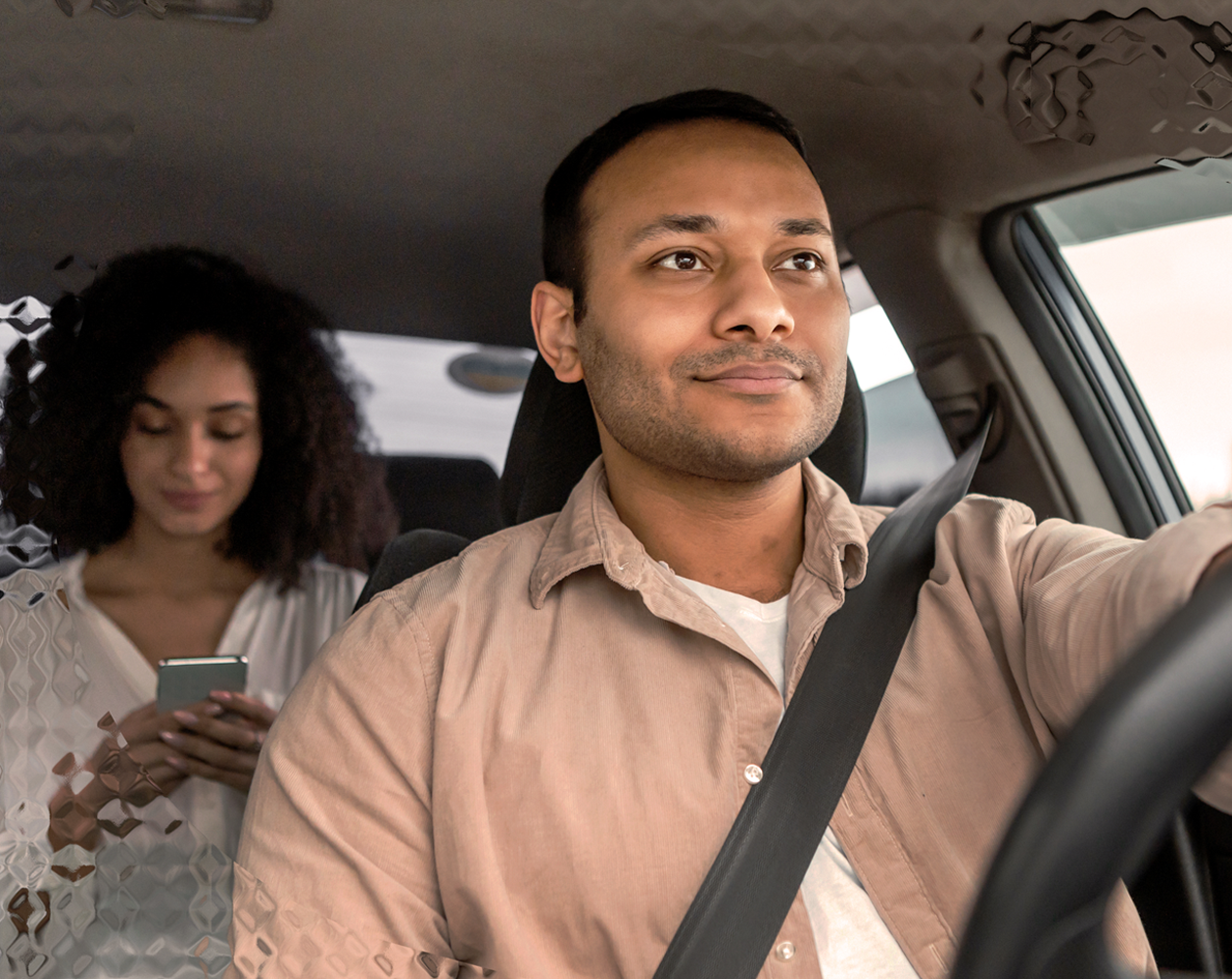 Image of a man driving a ride share car with a passenger at the back.