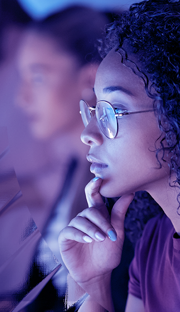 Image of a serious curly haired woman looking at her monitor