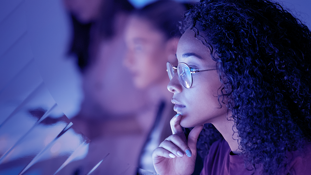 Image of a serious curly haired woman looking at her monitor