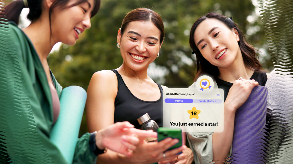 Women with yoga mats celebrating earning a point on a mobile app